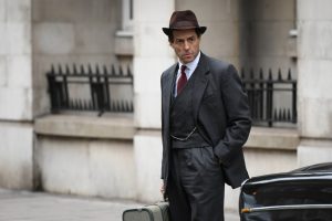 Actor Hugh Grant playing Jeremy Thorpe in hat and suit