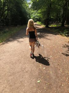 Woman in shorts carrying children's bicycle