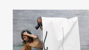 Victoria Beckham lies in a branded carrier bag as she celebrates 10 years in fashion