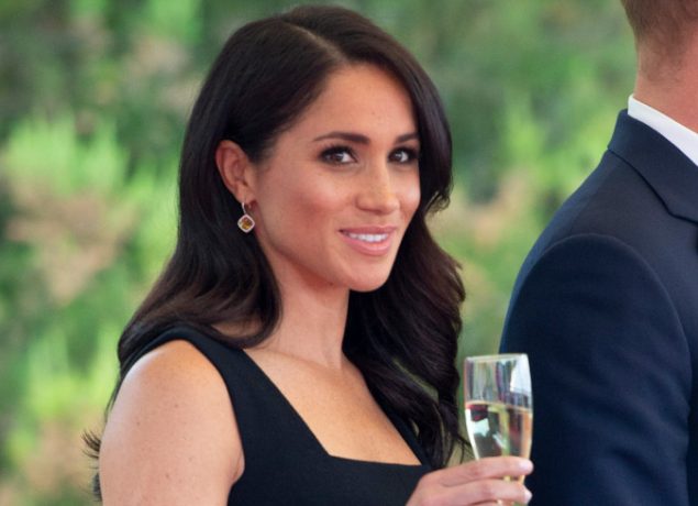 Meghan smiles with champagne glass
