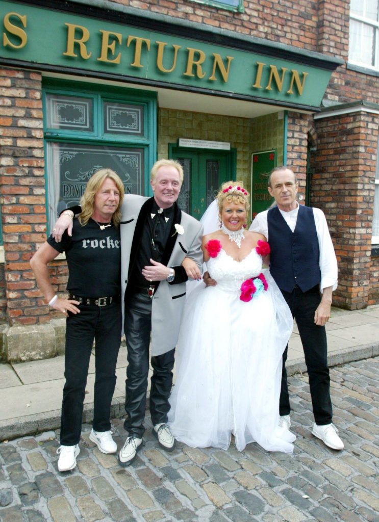 Coronation Street guest stars Status Quo smile with Les and Cilla on their wedding day outside the Rovers