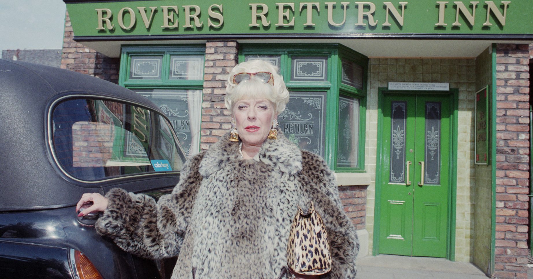 Editorial use only Mandatory Credit: Photo by Shutterstock (6374758l) Publicity shots of Julie Goodyear (as Bet Gilroy) (Episode 3922, 16th October 1995), as she leaves the Rover Return pub, in a taxi, in her iconic leopard-skin outfit. 'Coronation Street' TV Series - Oct 1995