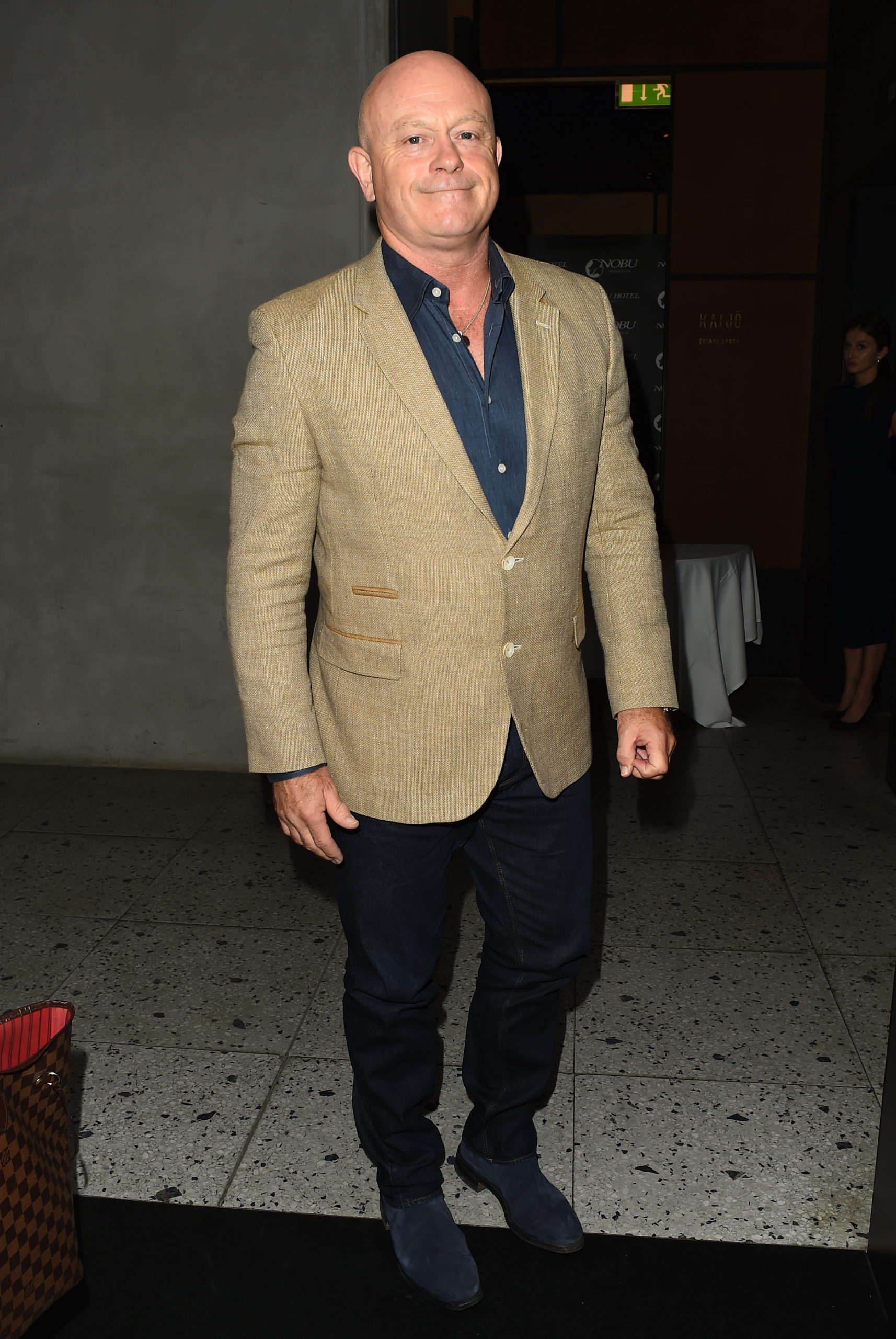 Ross Kemp posing in a beige jacket and jeans