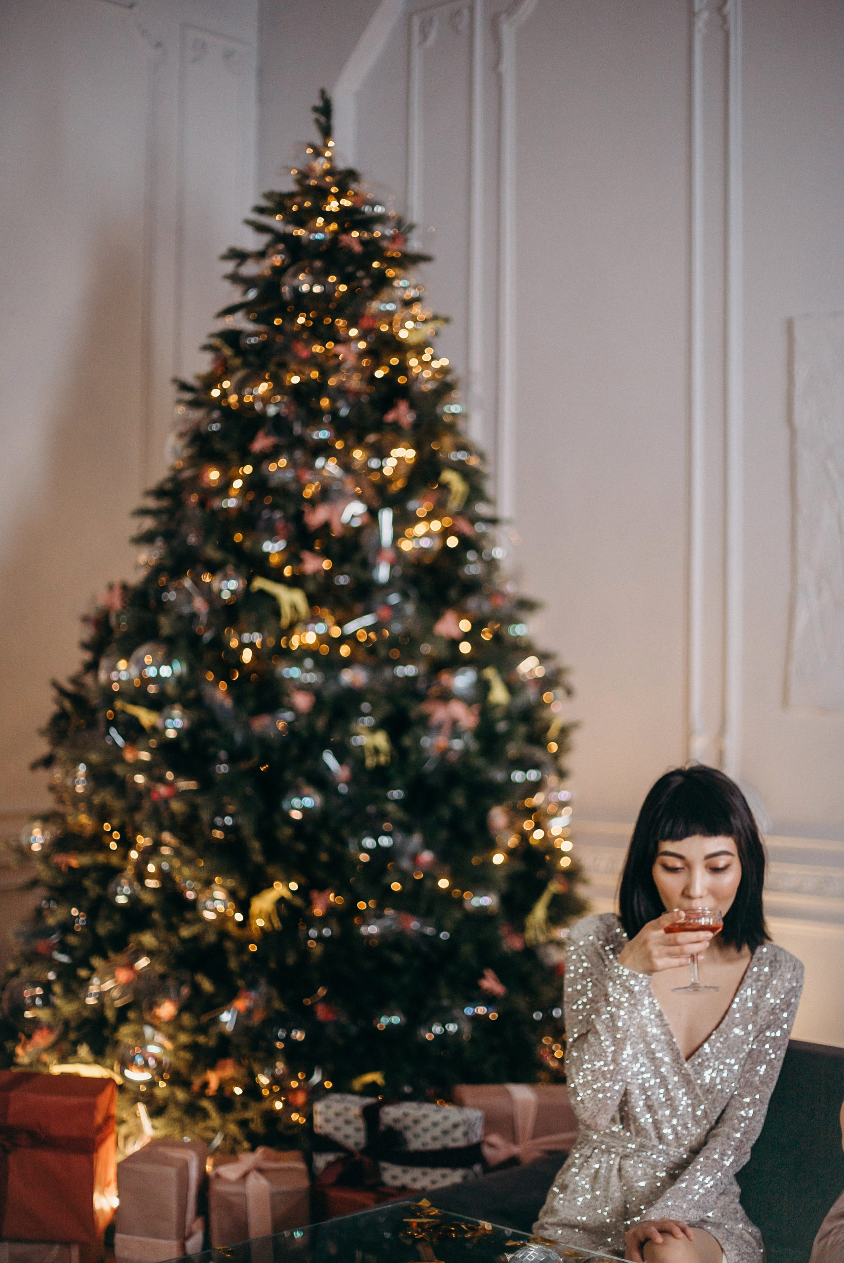 Woman drinking cocktails in front of a Christmas tree