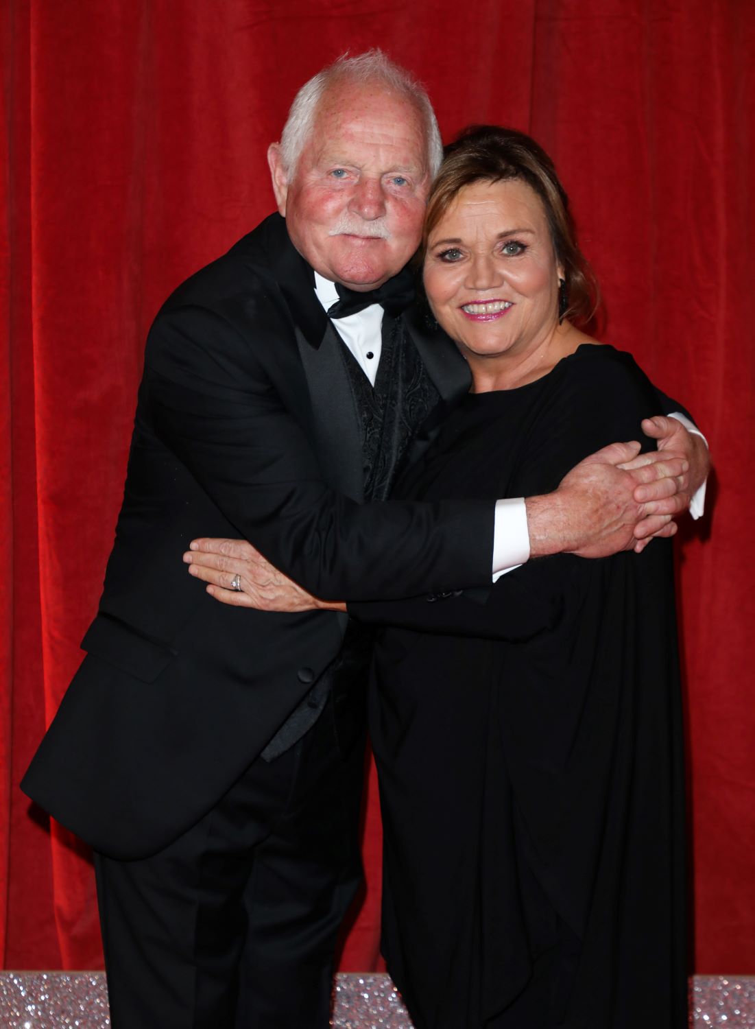 Chris Chittell and Lesley Dunlop cuddle closely on the red carpet dressed in black