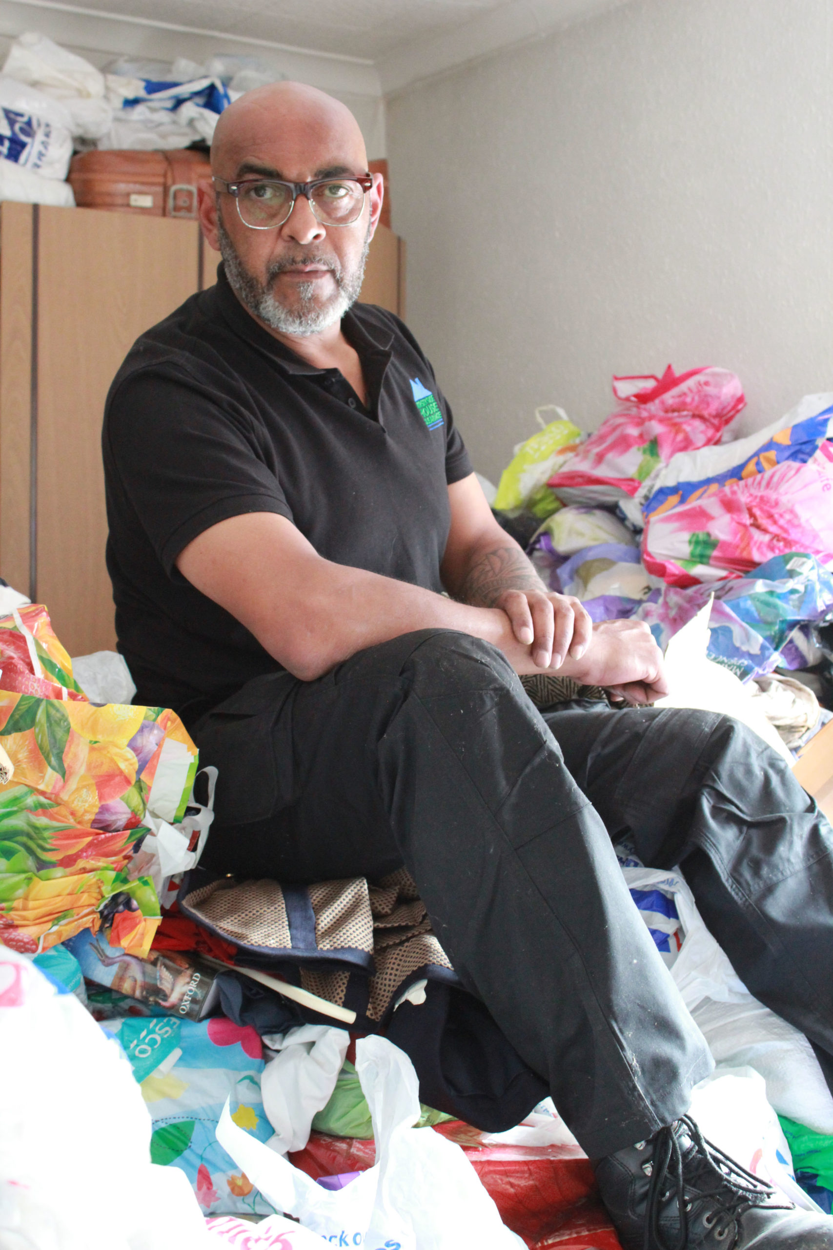 George the cleaner sits on Anne Marie's mountain of hoarded books (Credit: Channel 5)