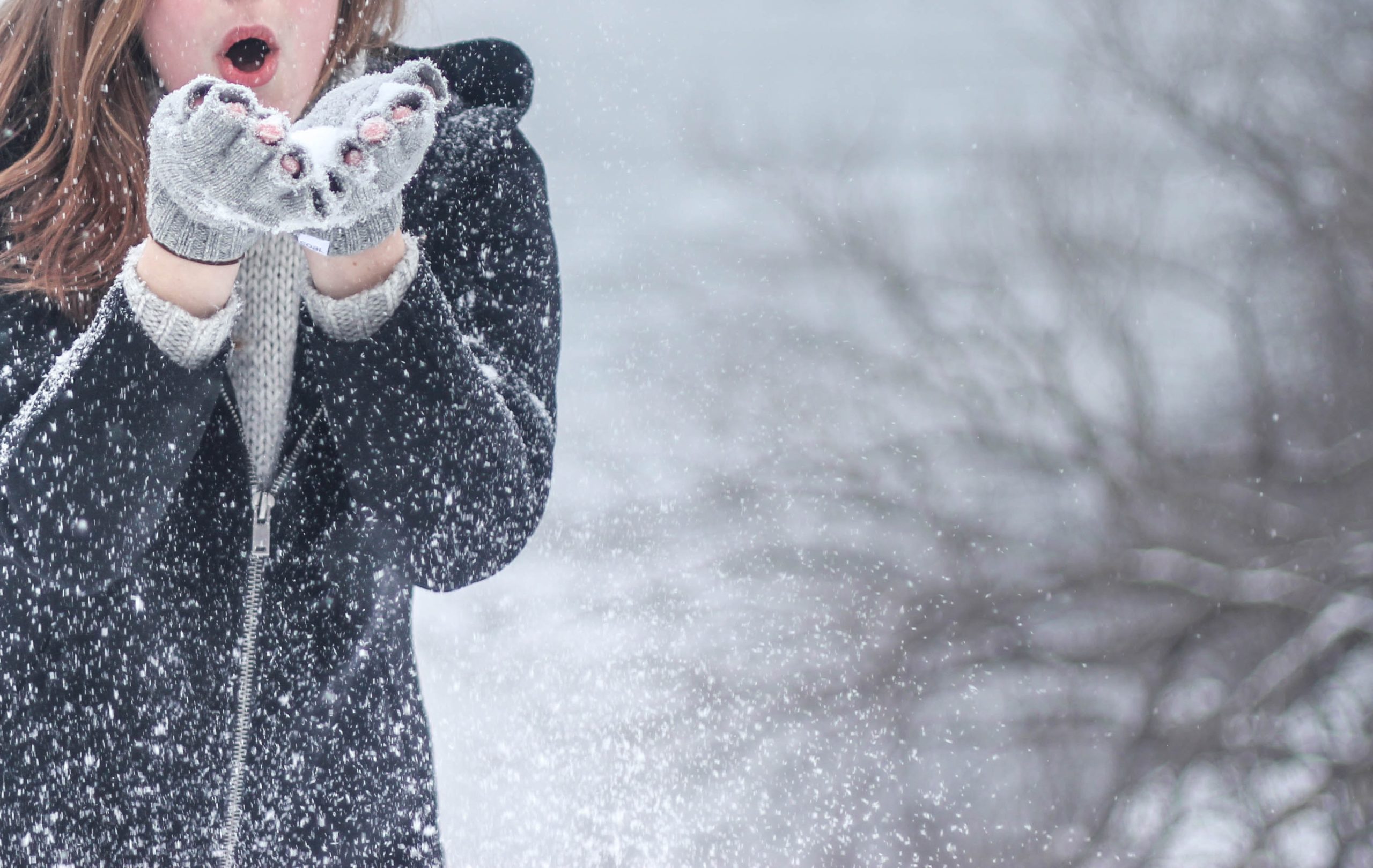 woman blowing snow wearing gloves