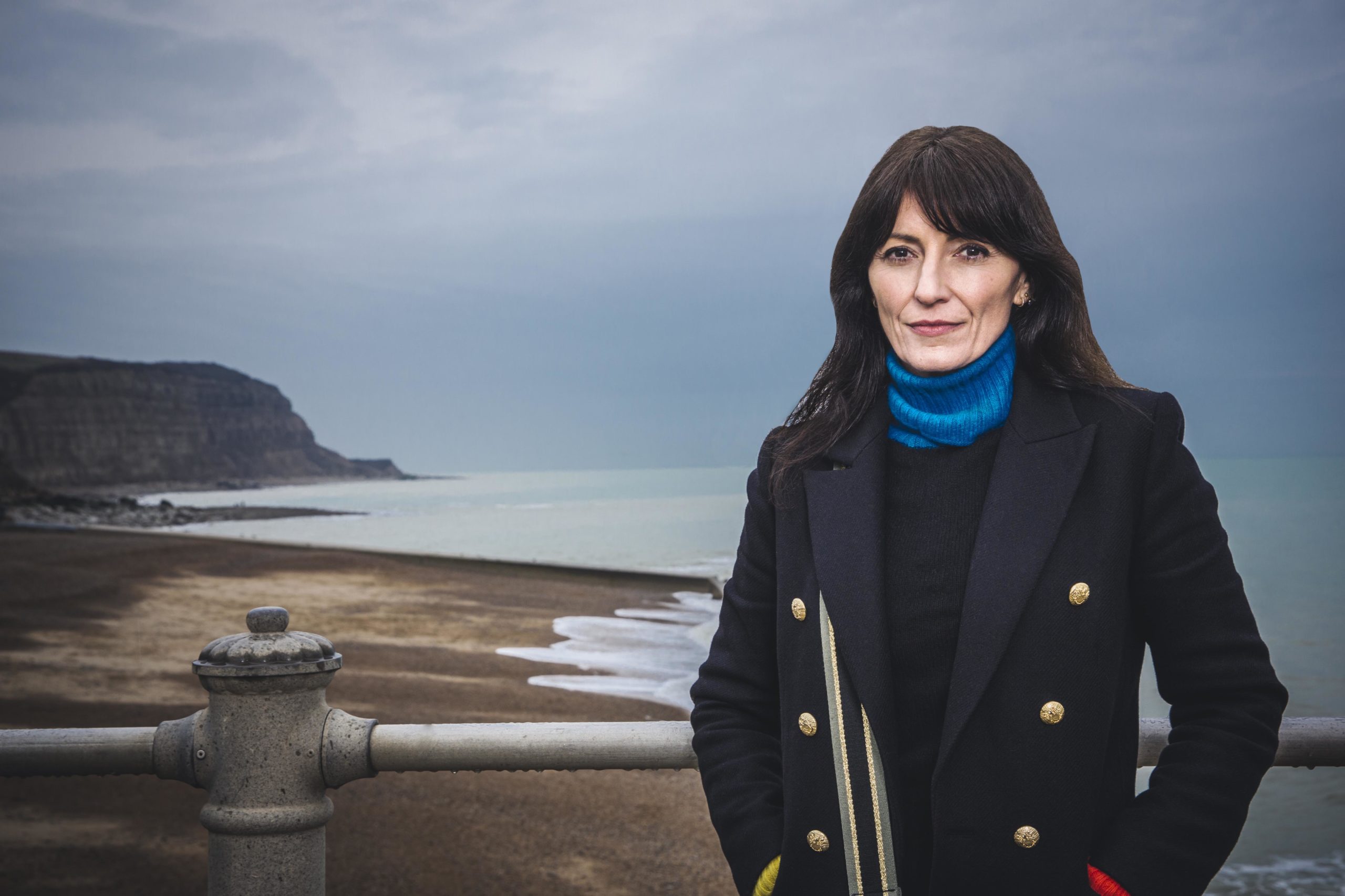 Davina McCall standing on a gloomy beach in a coat