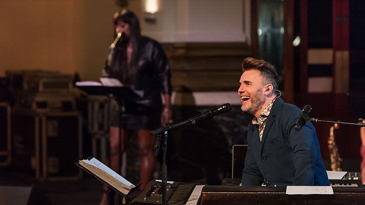 Gary Barlow smiles at the piano on the set of his new tv show