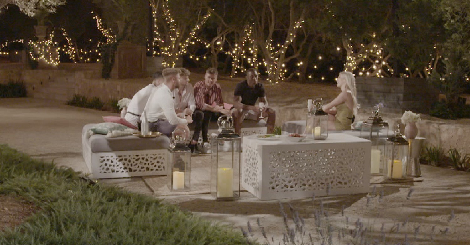 Love Island contestants sitting around the fire in the evening