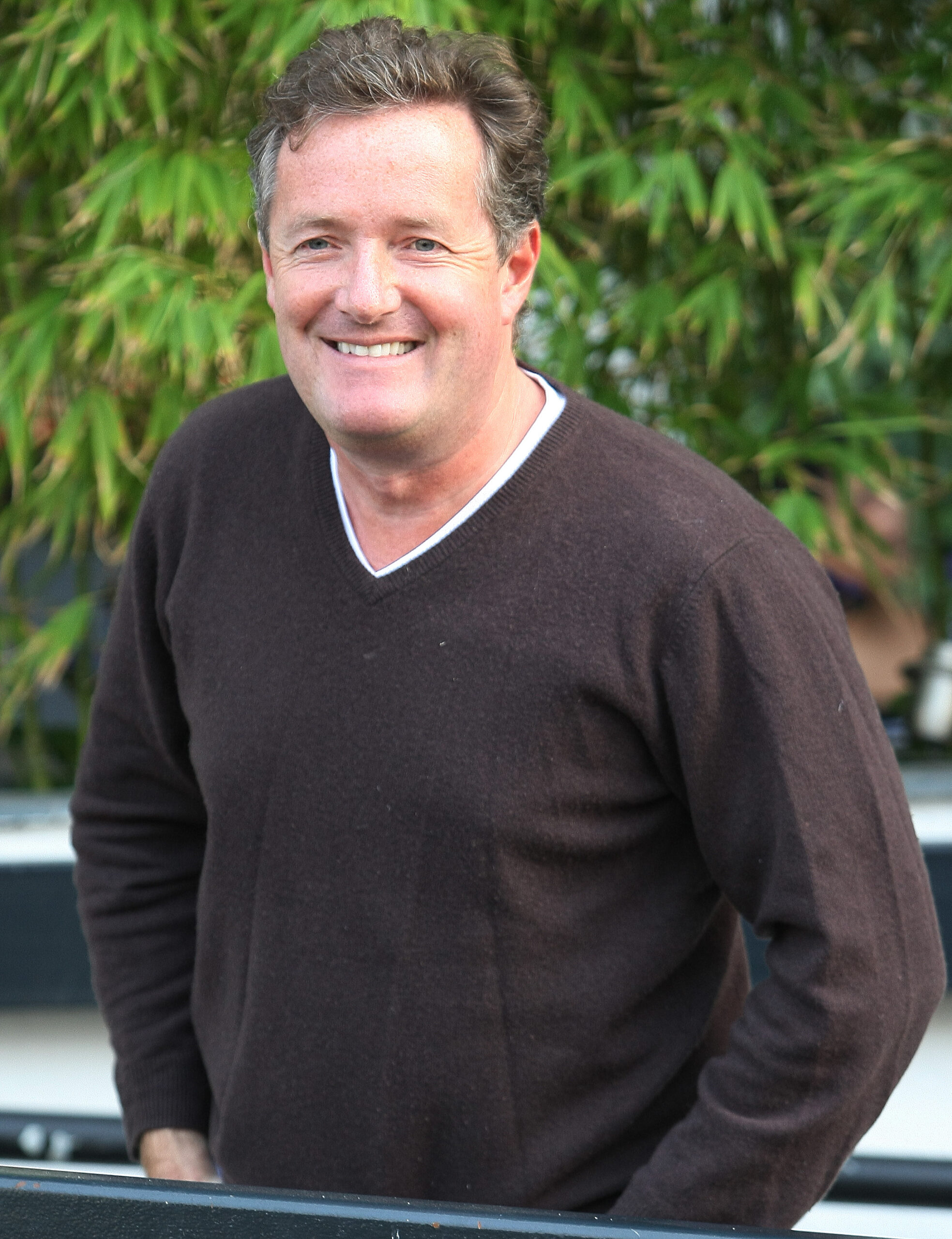 Piers Morgan twitter: Star smiles wearing a grey v neck jumper 