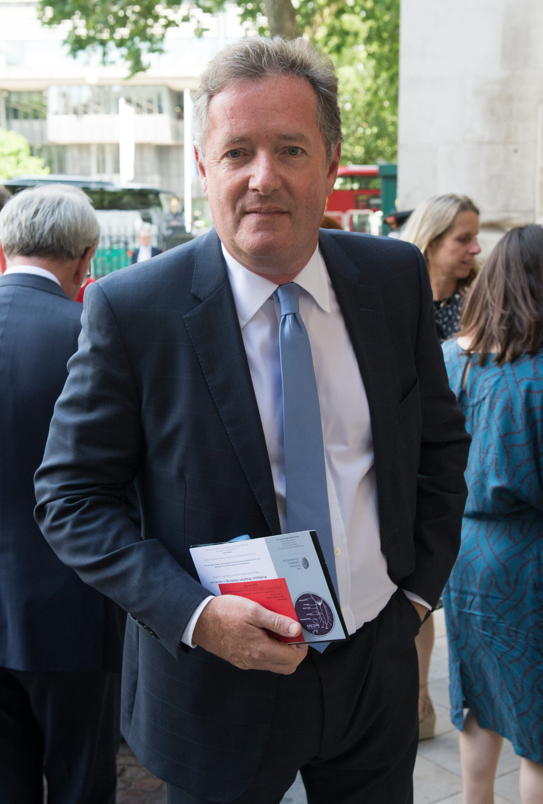 Piers Morgan in a blue suit and white shirt with baby blue tie