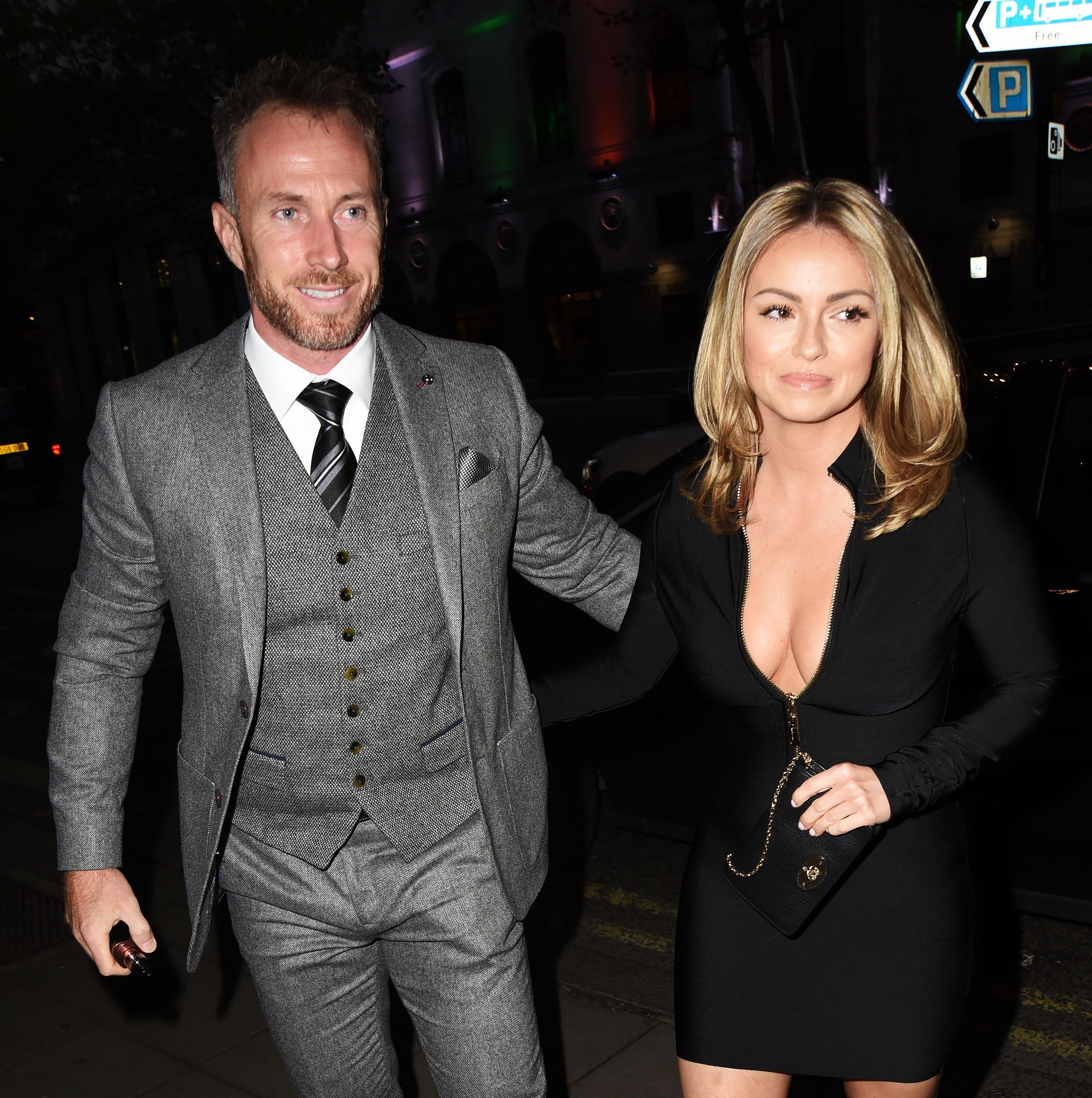 James Jordan dressed in a grey three piece suit with one arm around his wife Ola Jordan wearing a long sleeved black zip up mini dress
