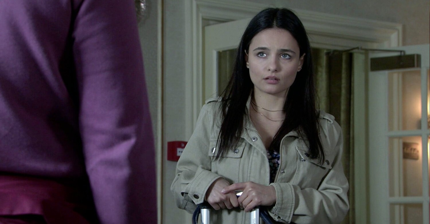 Alina is looking upset as she holds her suitcase in Coronation Street