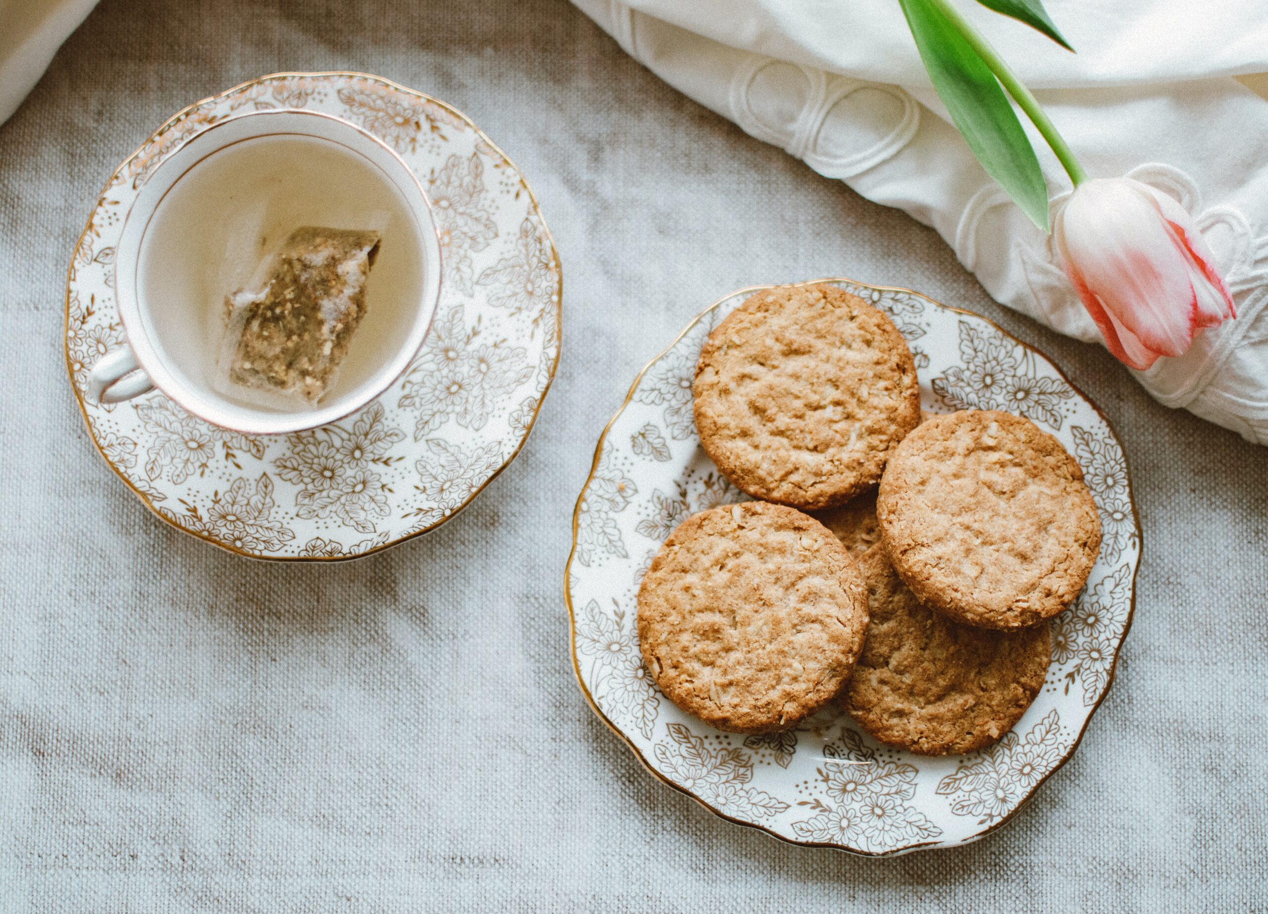 Oat biscuits and a cup of tea on a marble table with a pink rose