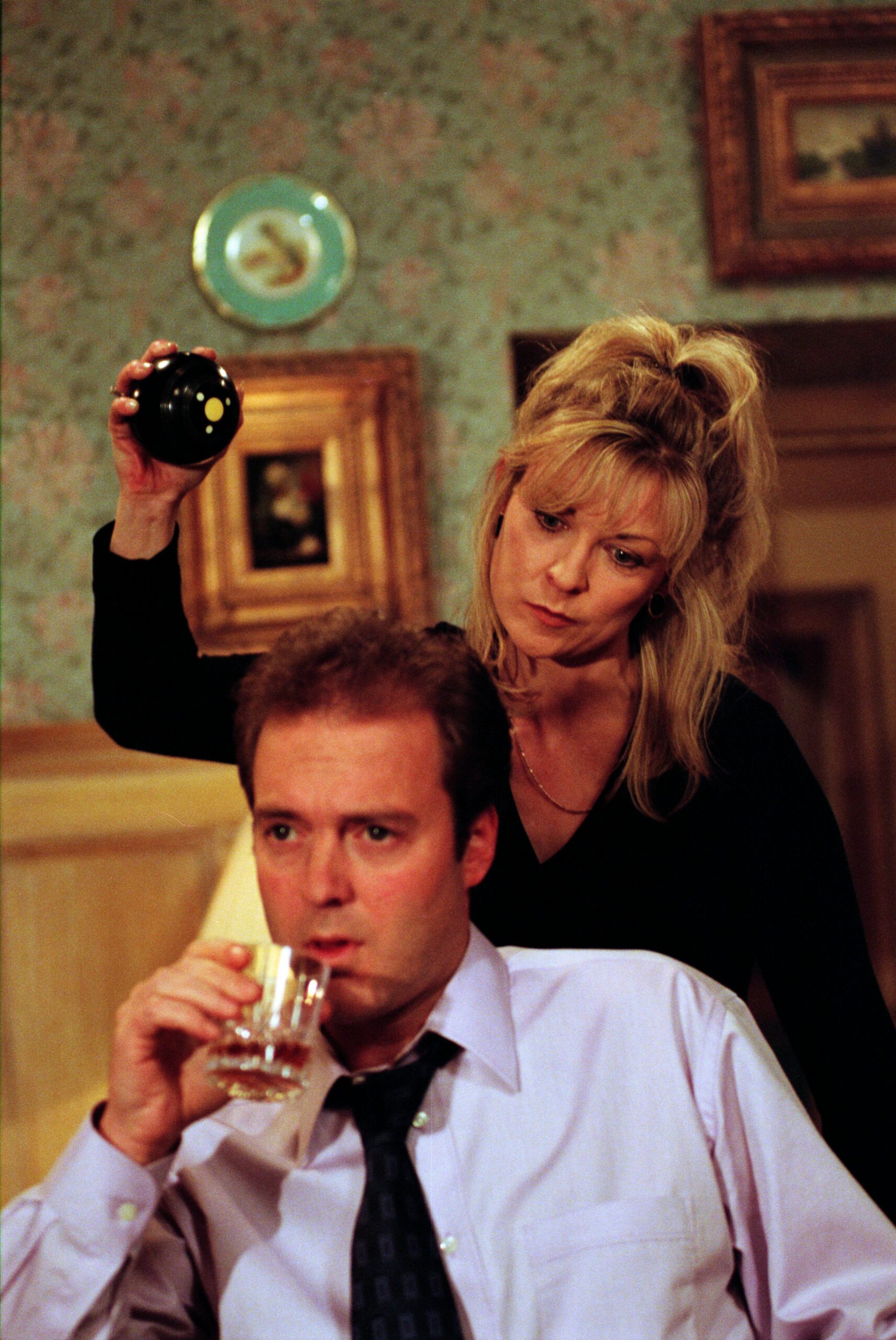 Emmerdale Kim Tate whacks Chris Tate over the head with an ornament as he drinks whiskey