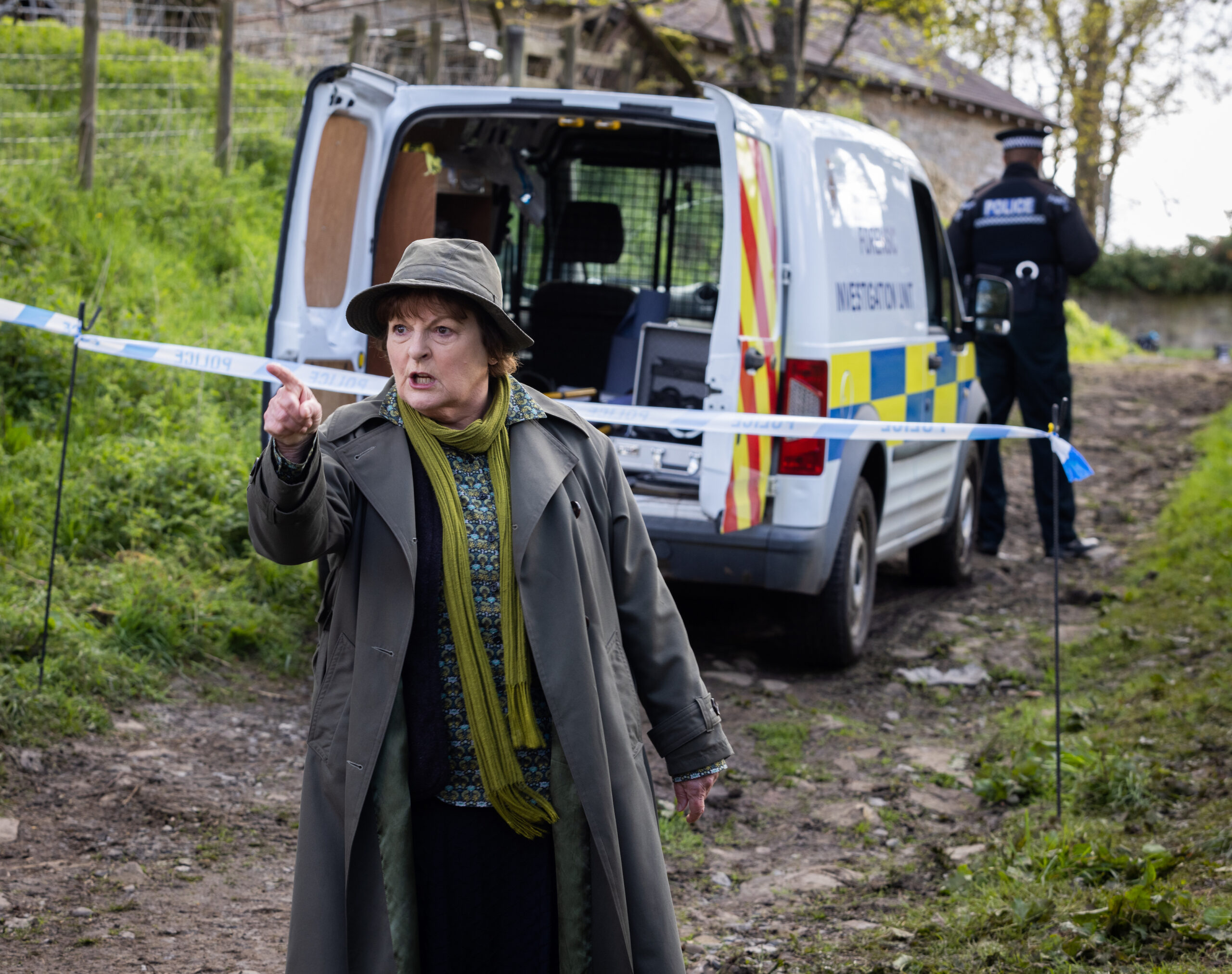 Vera actress Brenda Blethyn in character pointing her finger in front of a police van