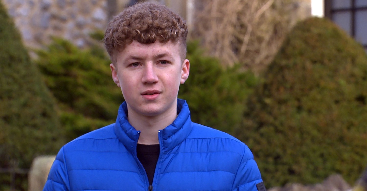 Noah in Emmerdale dressed in a bright blue coat staring into the distance