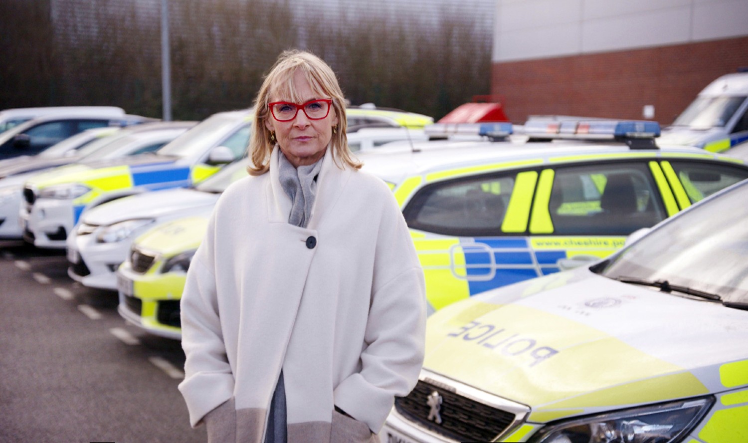 Louise Minchin standing in front of police cars