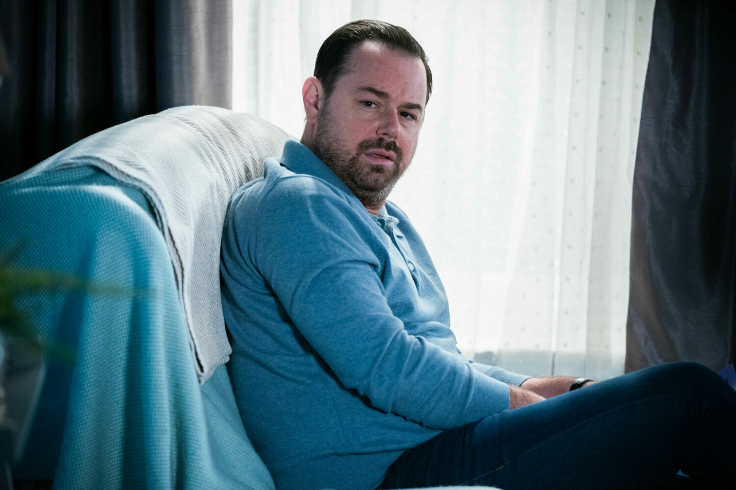 Mick Carter in EastEnders looking bewildered on the sofs (Credit: BBC)