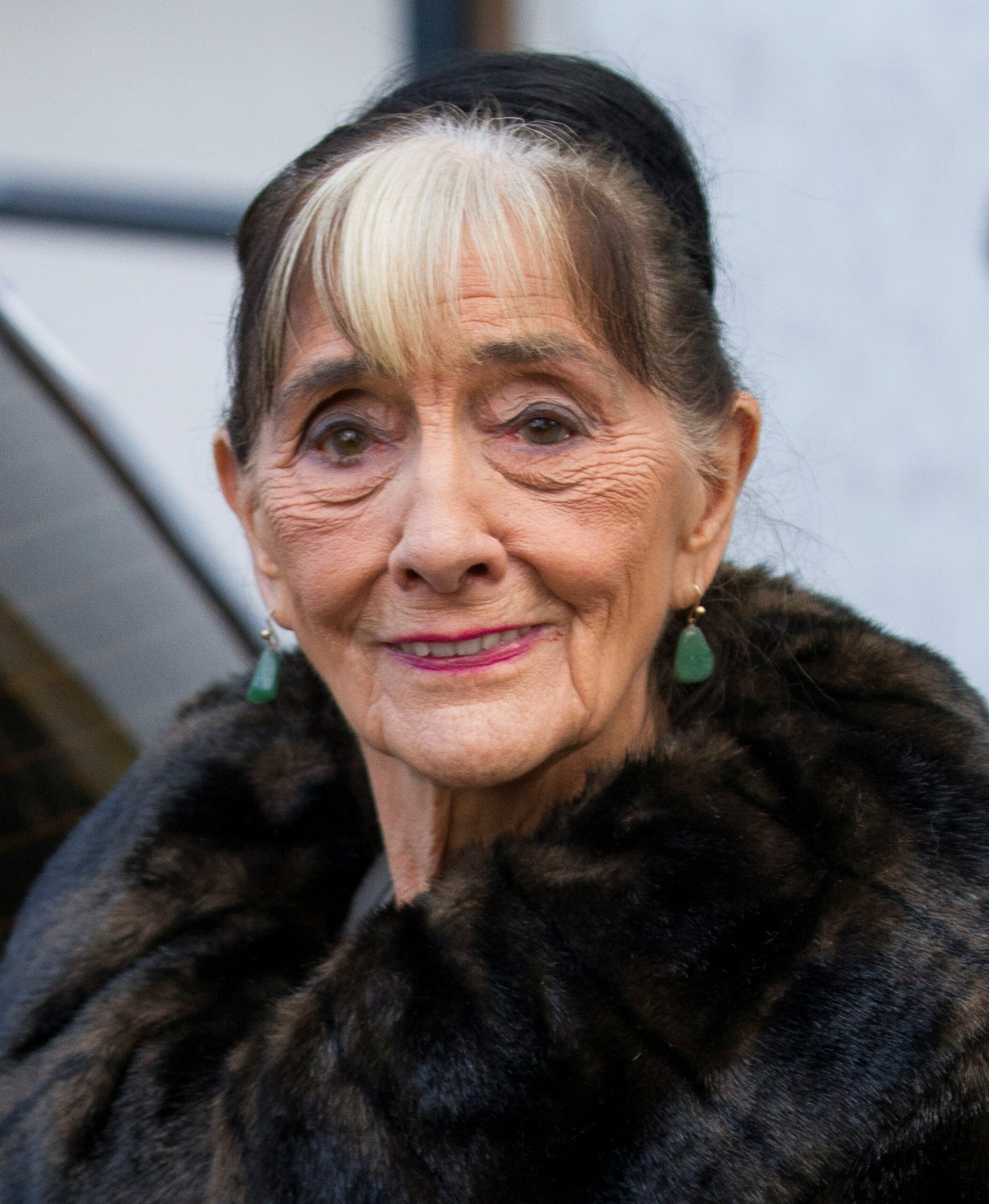 June Brown smiles for cameras in fur coat