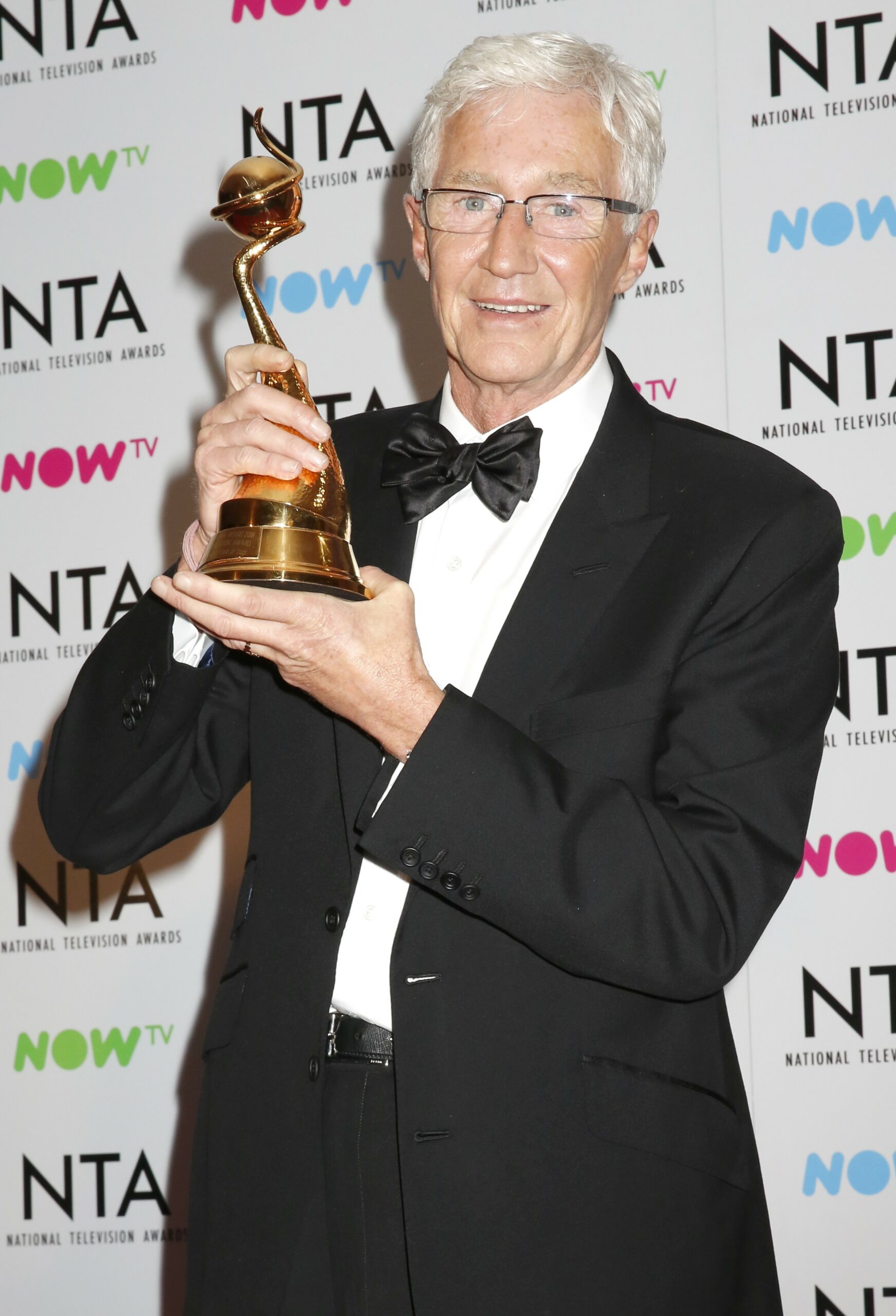Paul O'Grady smiling while holding an NTA 
