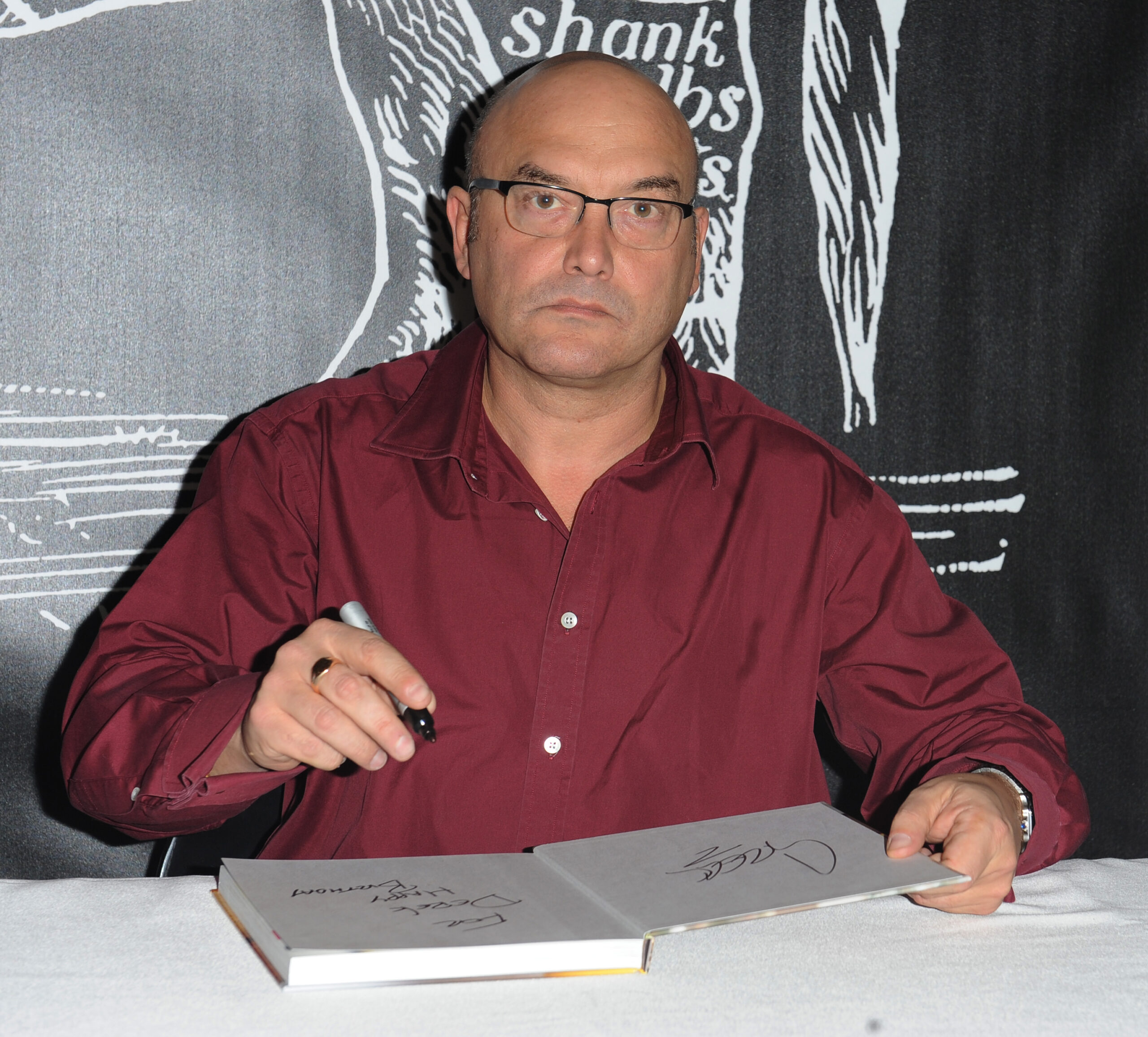 Masterchef star Gregg Wallace signing books in burgundy shirt