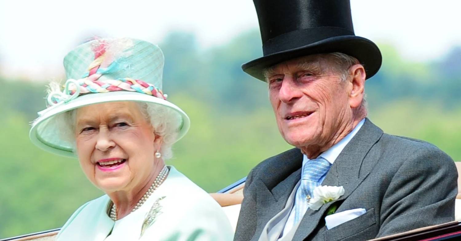 The Queen and Prince Philip smile for the cameras from their cart on an engagement