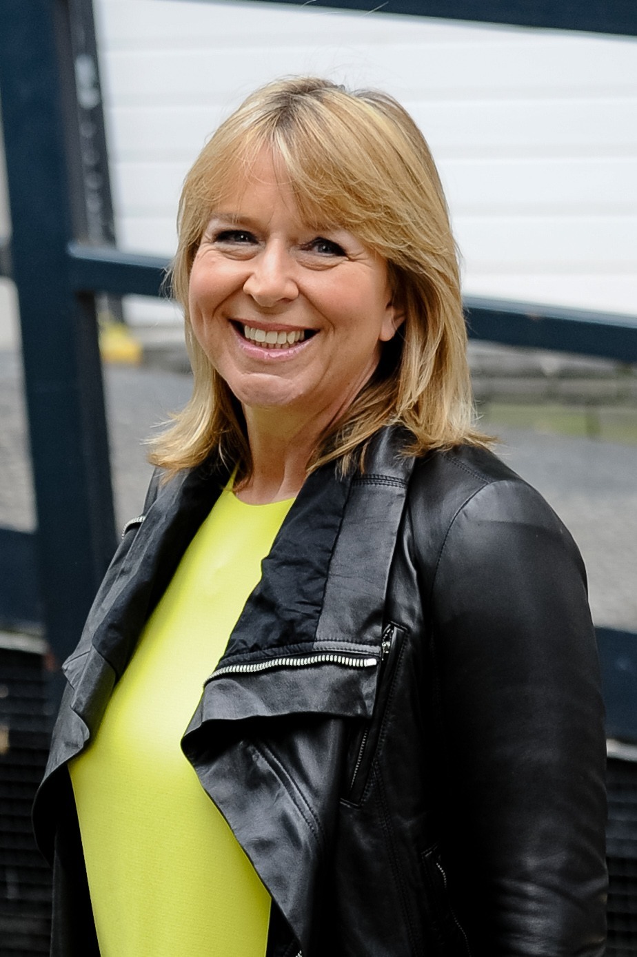 Fern Britton smiles at cameras in yellow top outside ITV studios