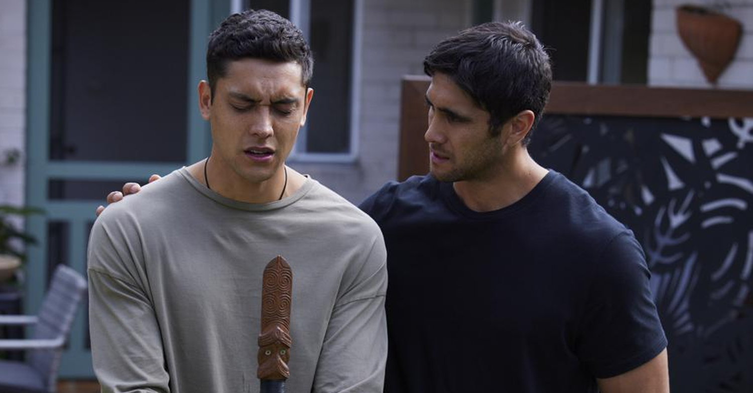 Home and Away Nik and Tane, hand on shoulder holding Maori stick 