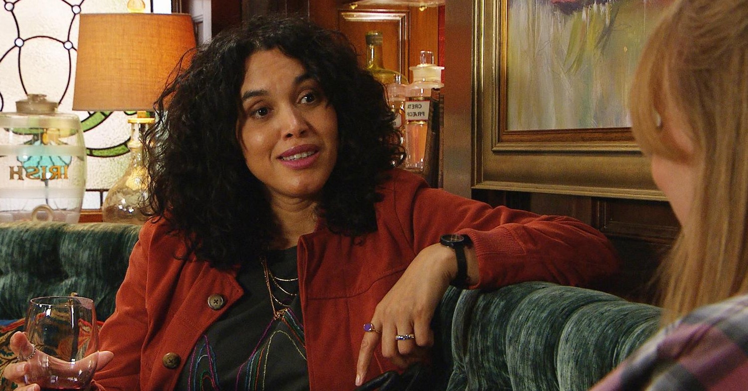 Suzy from Emmerdale smiling in The Woolpack, drink in hand (Credit: ITV)