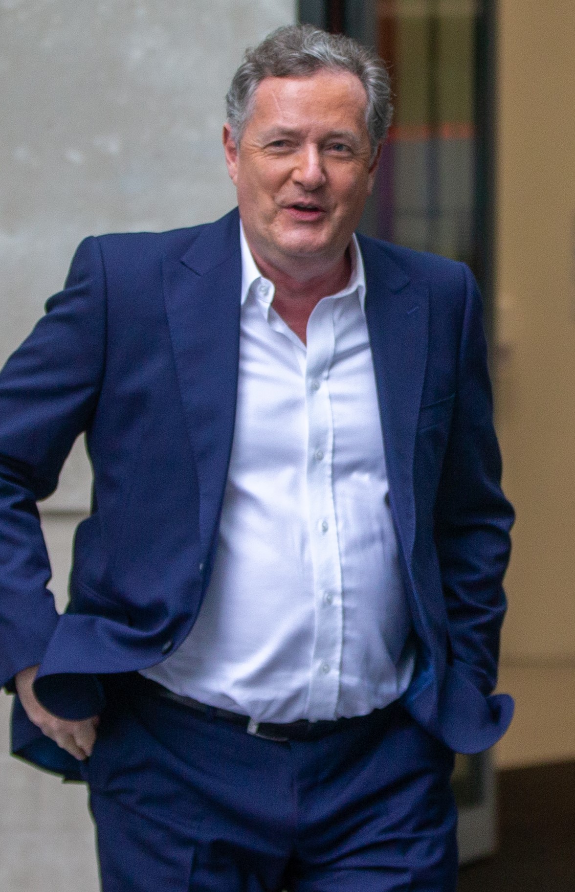 Piers Morgan smiles in navy suit during outing