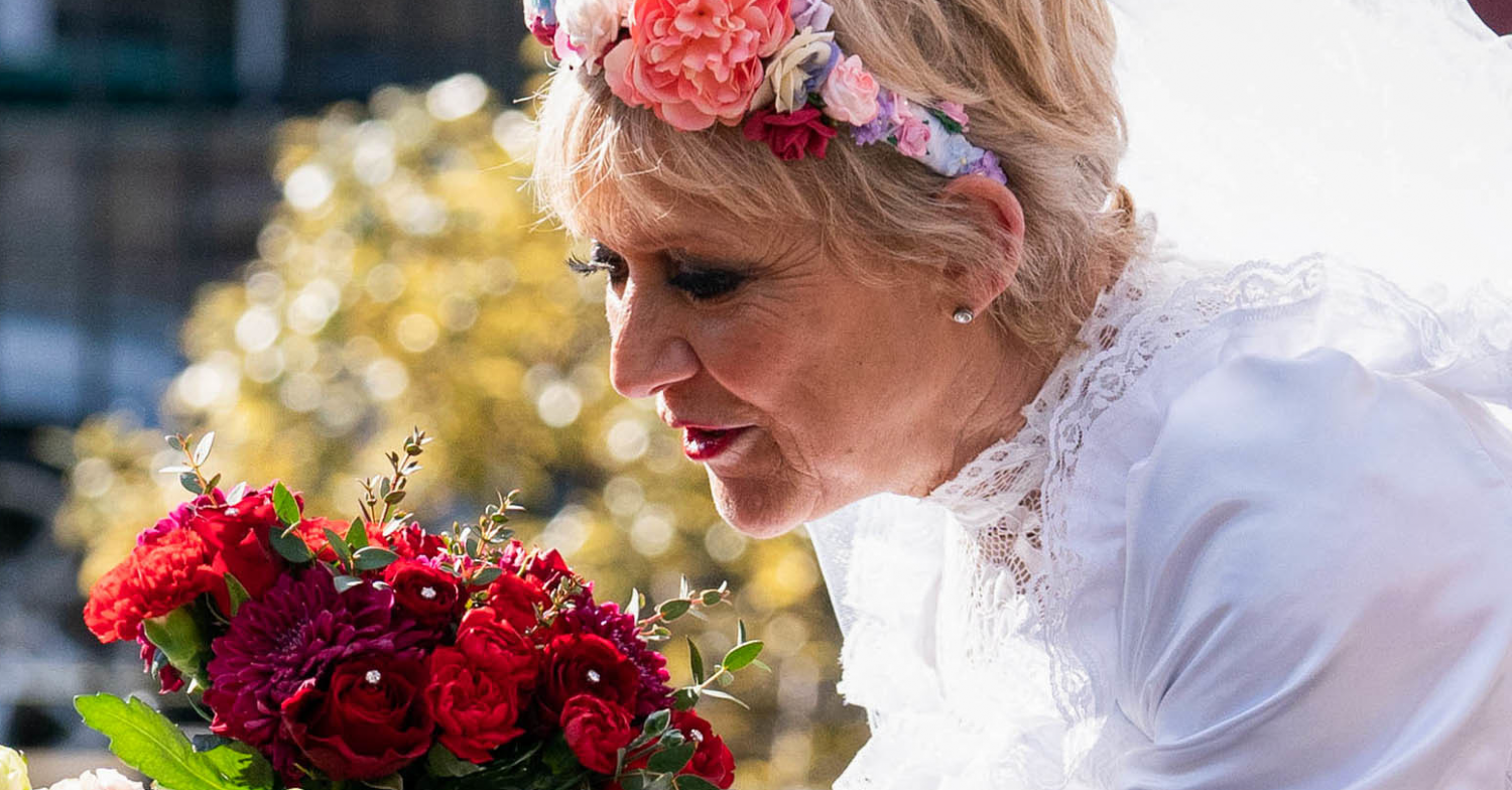 EastEnders Jean in wedding dress smelling flowers