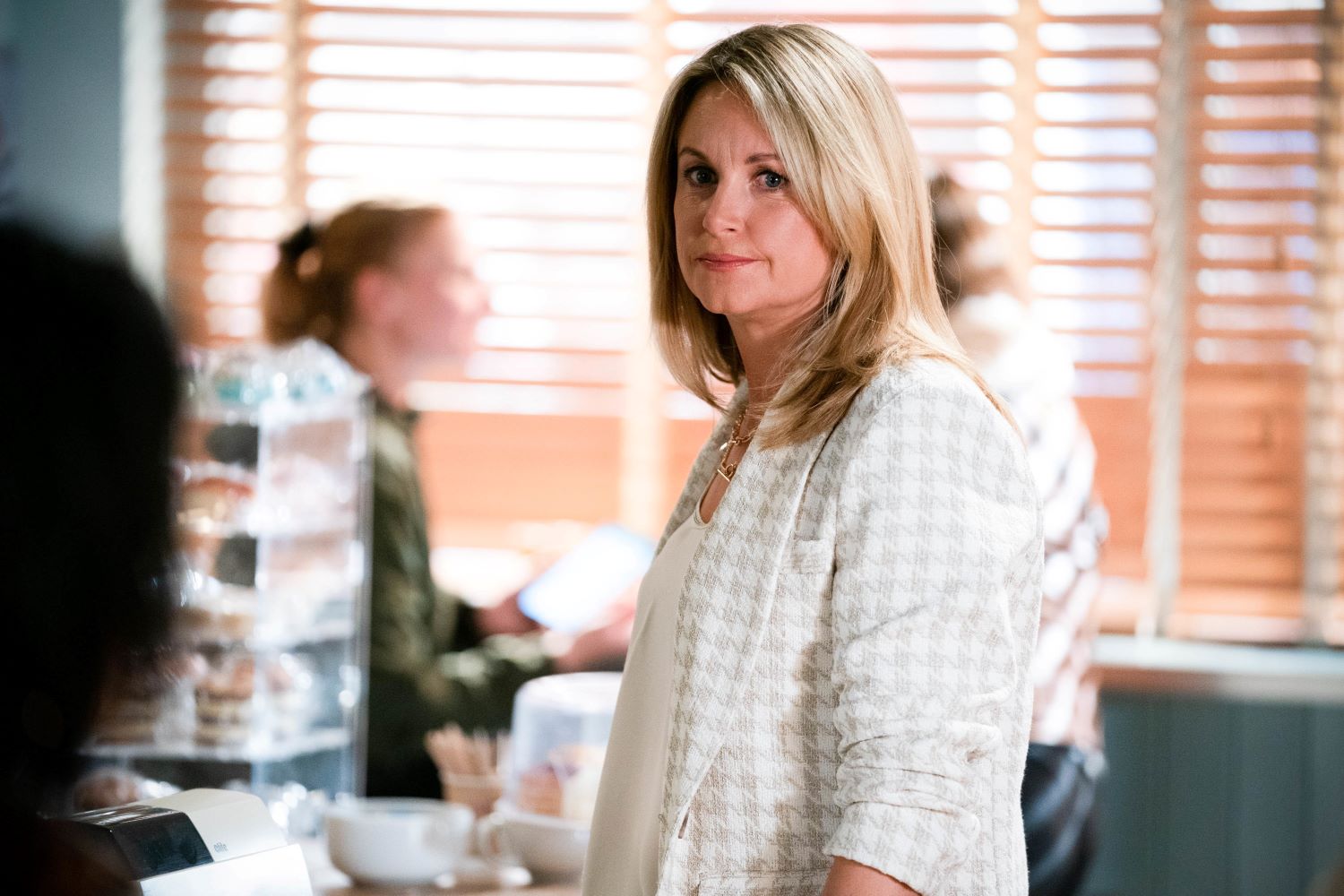 Sam Mitchell is plotting as she looks at Kat in the cafe