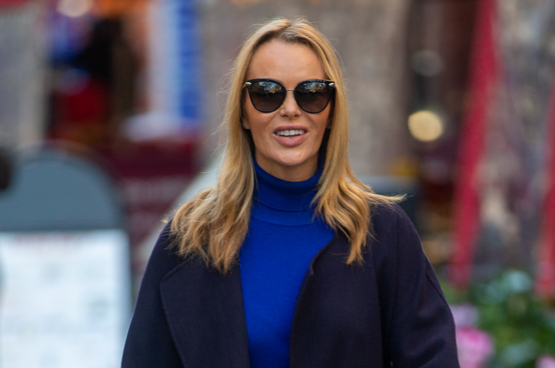 Amanda Holden smiling wearing sunglasses and a blue jumper