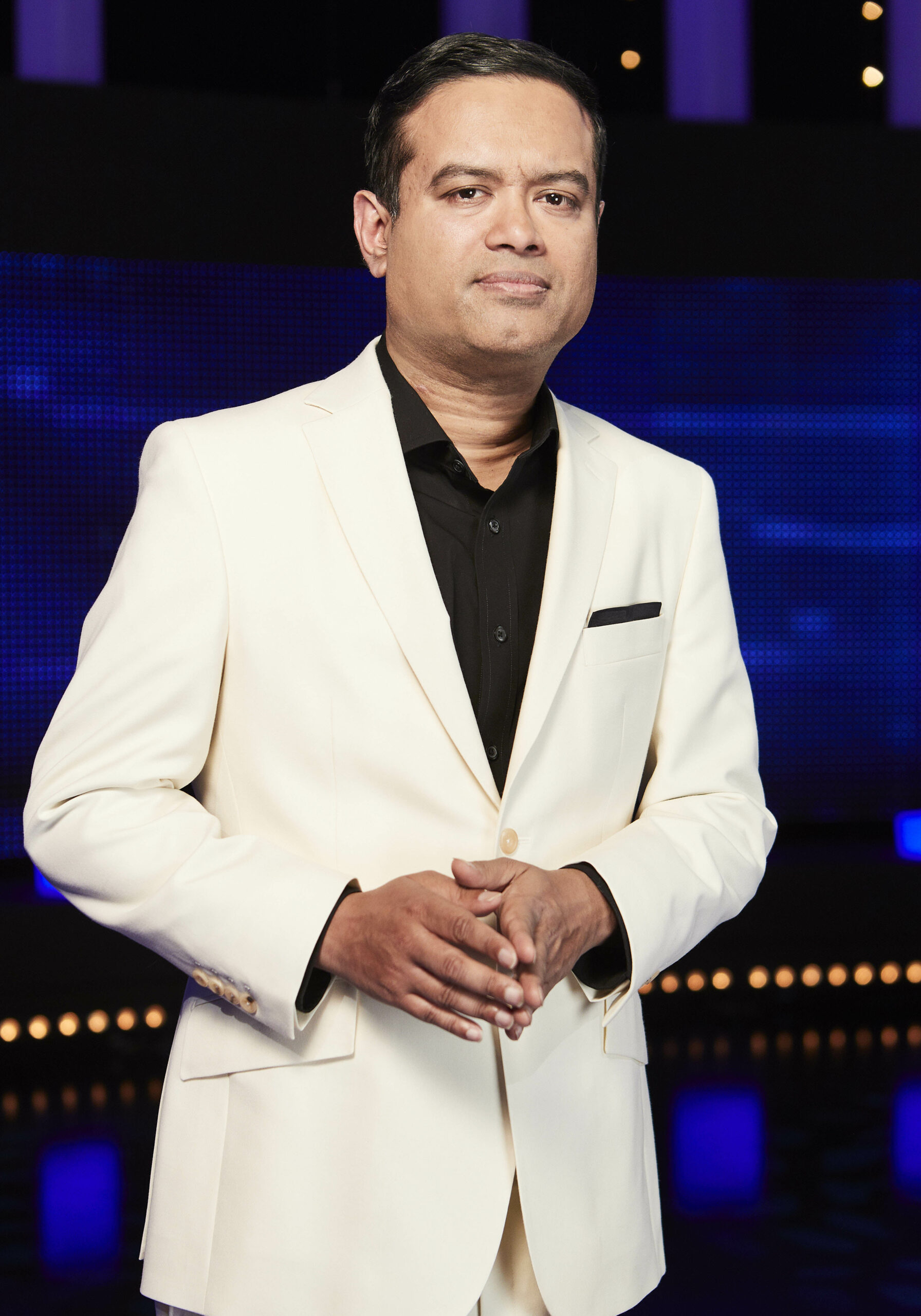 Paul Sinha wearing a white suit