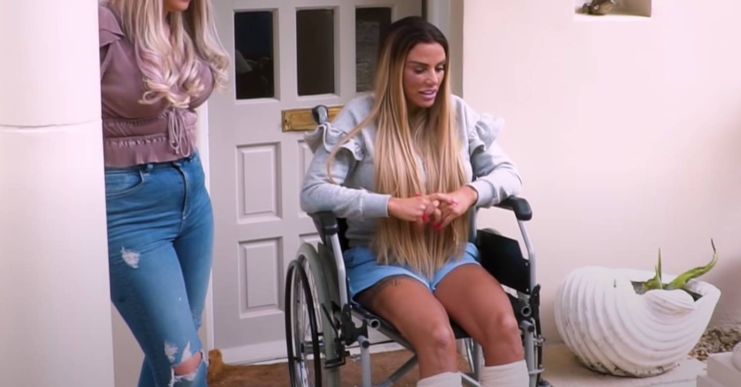 Katie Price looks down as she sits in a wheelchair
