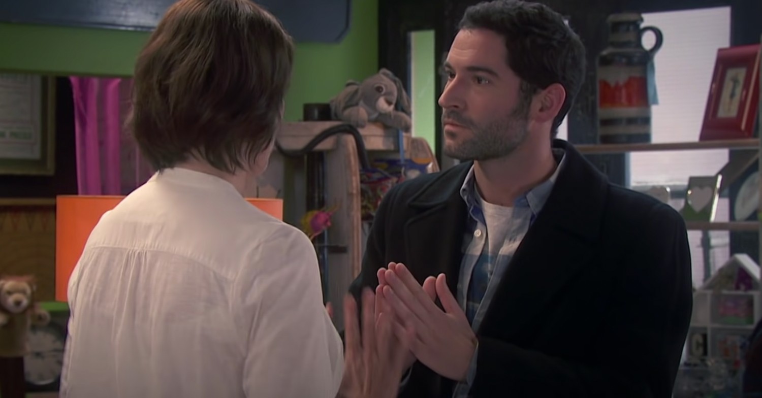 Tom Ellis talking to Miranda wearing jacket over casual clothes