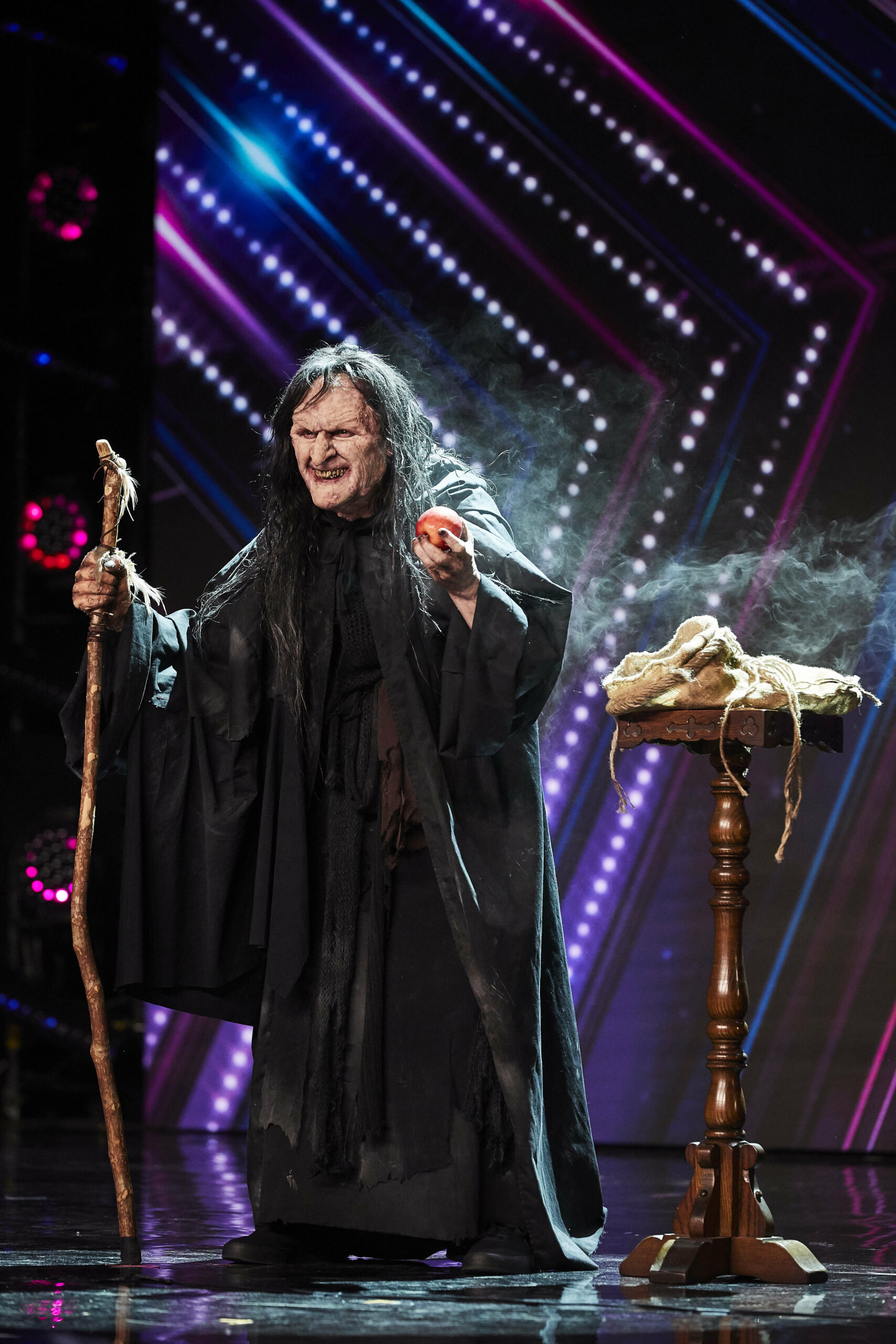 The witch on Britain's Got Talent snarls and holds an apple out