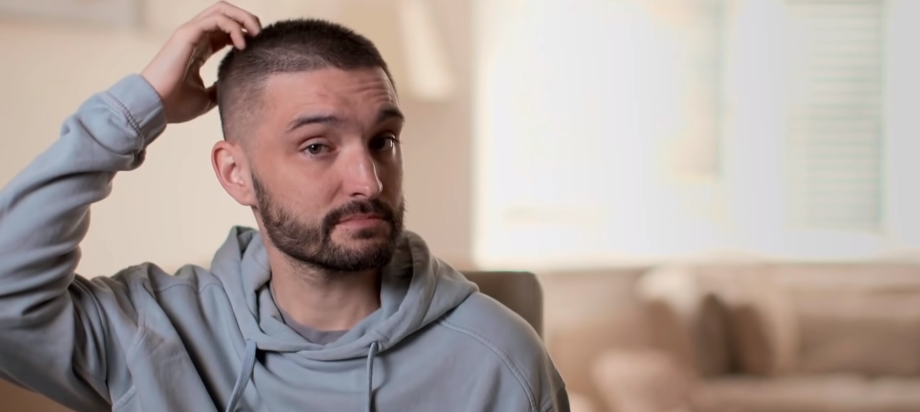 Tom Parker scratches his head as he talks about his brain tumour