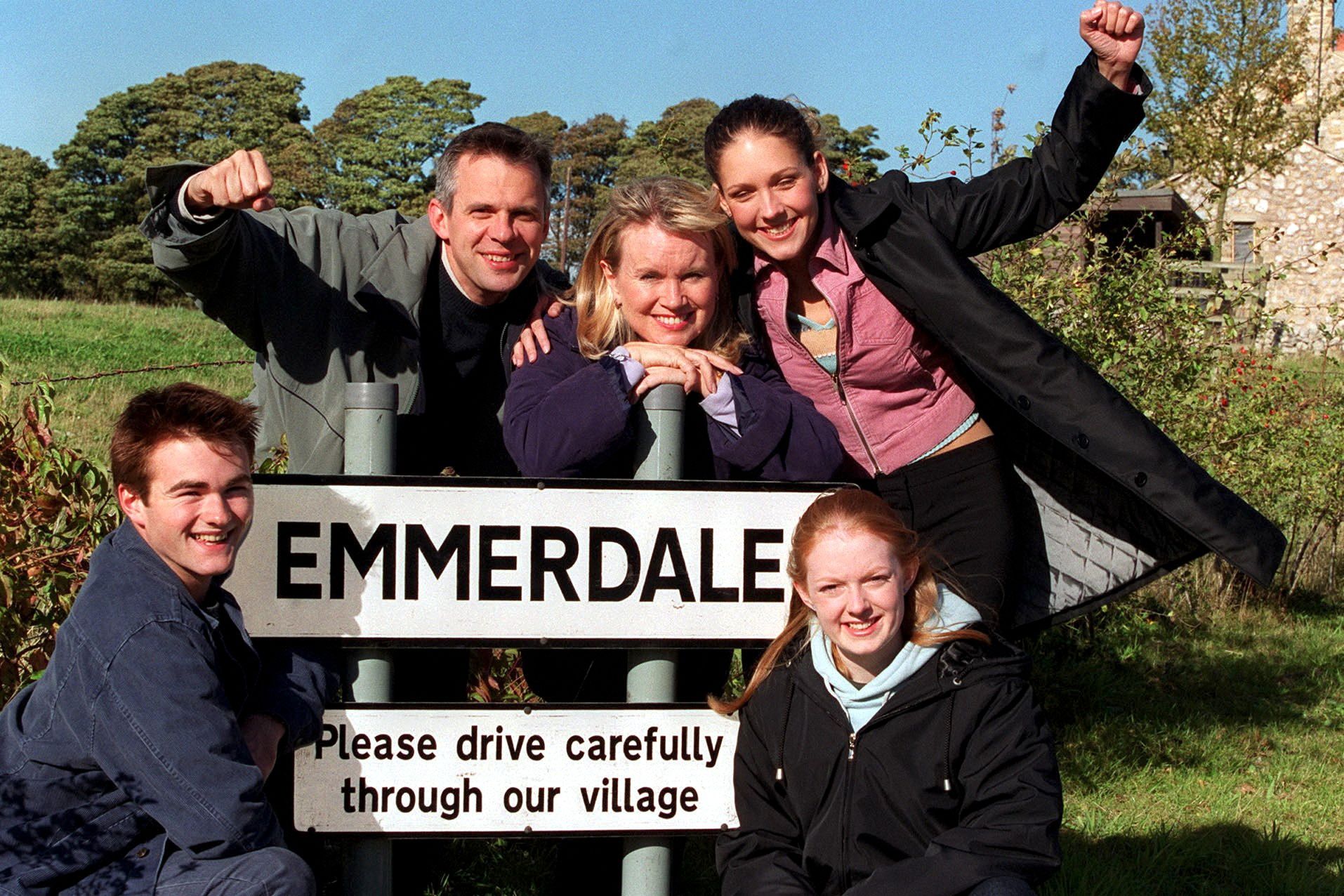Emmerdale Soapstars family pose with the village sign