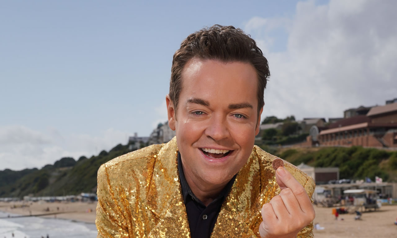 Stephen Mulhern wearing a gold sparkly jacket on the beach 