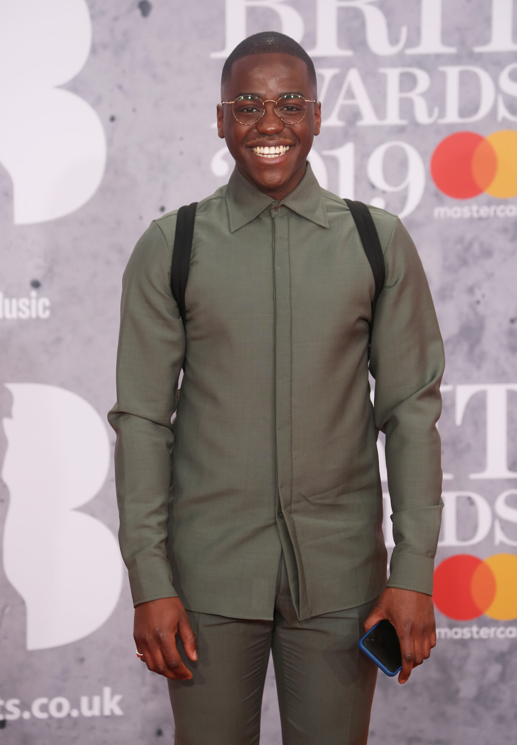 Ncuti Gatwa smiling wearing glasses on the Brits red carpet