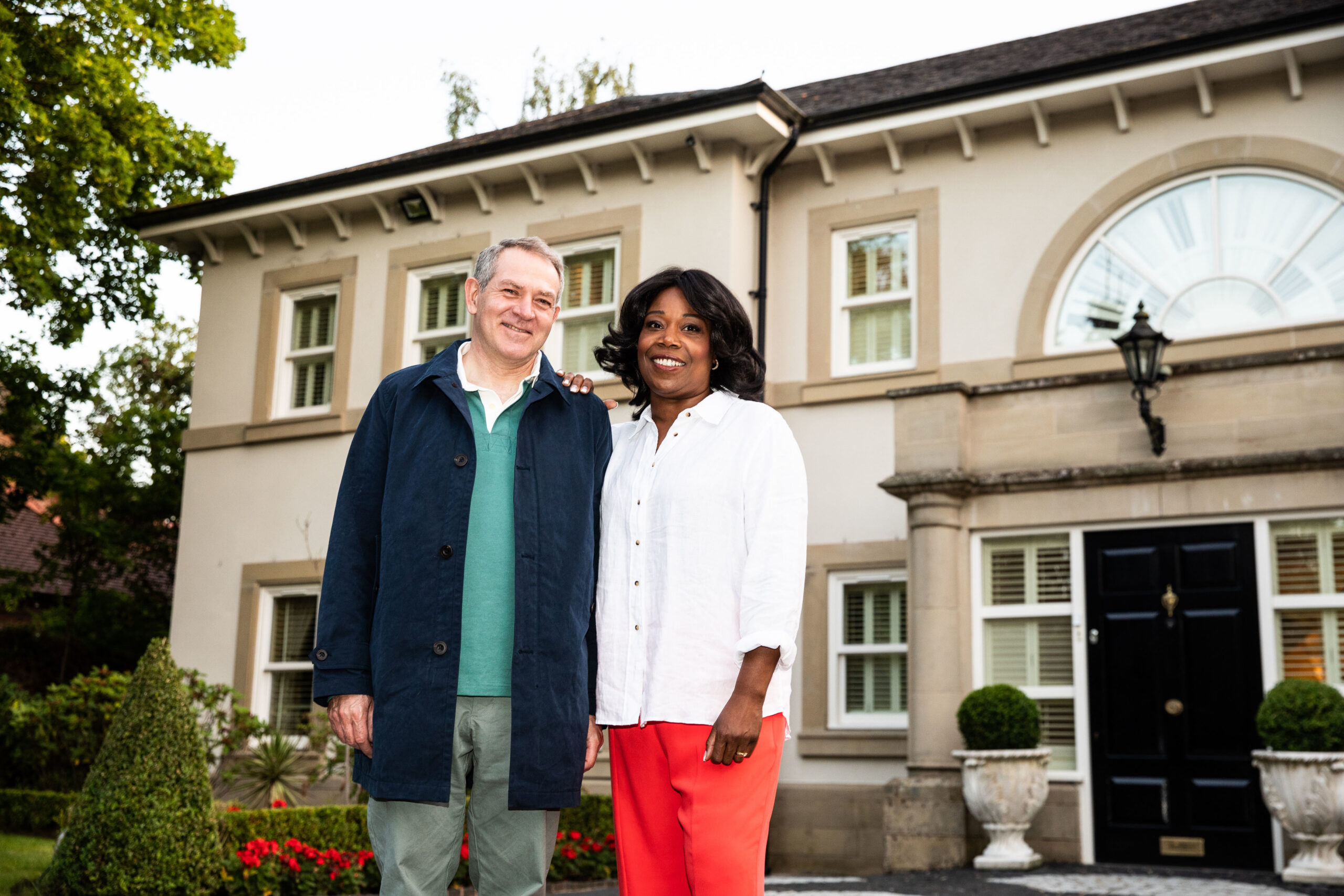 Michele Austin smiling in front of a plush home
