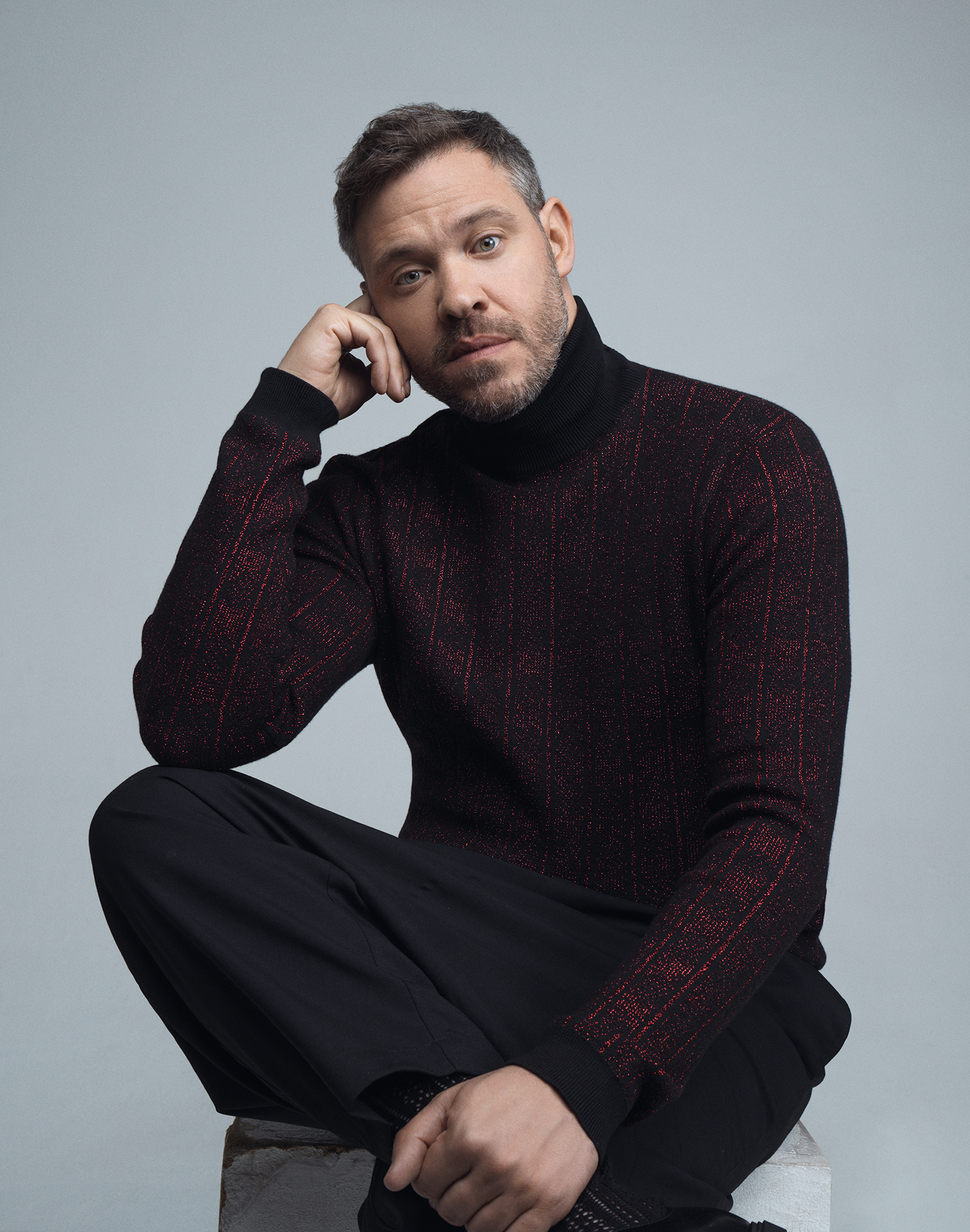 Will Young posing against a grey background wearing a roll neck jumper