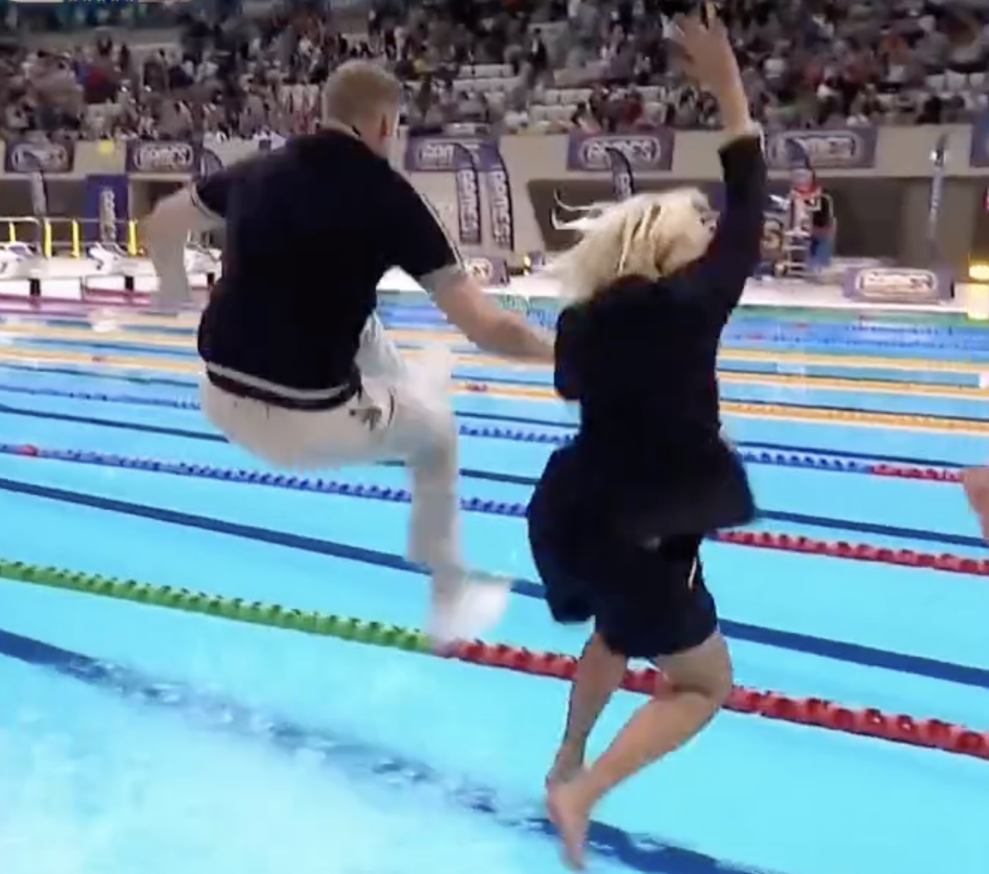 Freddie Flintoff and Holly Willoughby with their backs to camera, jumping into a swimming pool, fully clothed on The Games 2022