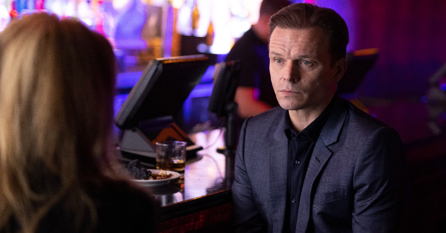 Grace cast member Alex Newman sitting in a bar as Joe Baker