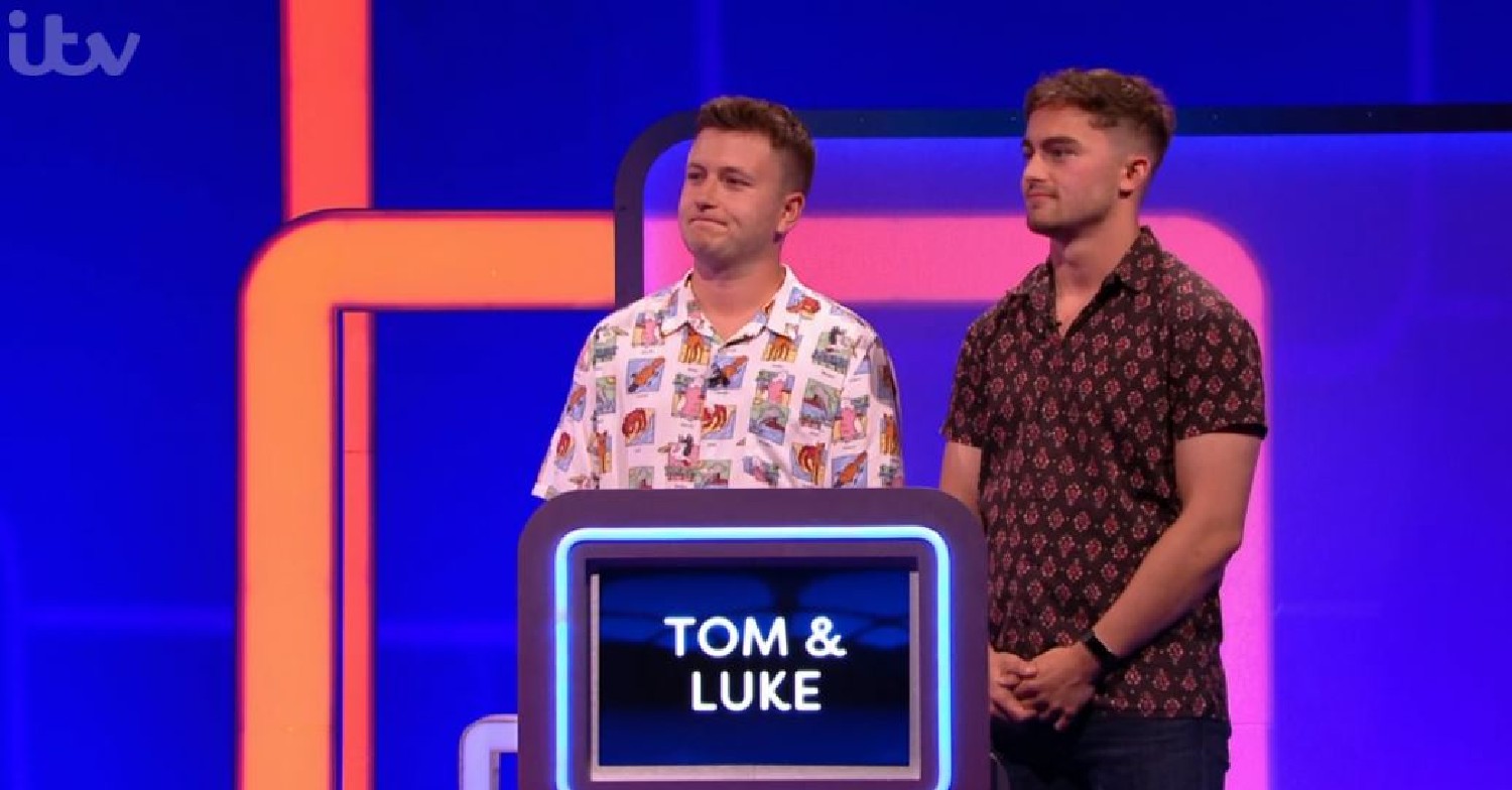 Tom and Luke stood behind a podium with their name on it on Lingo