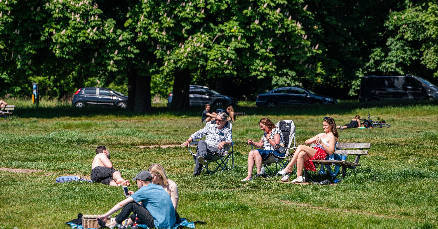 People sunbathing in a park during UK weather heatwave