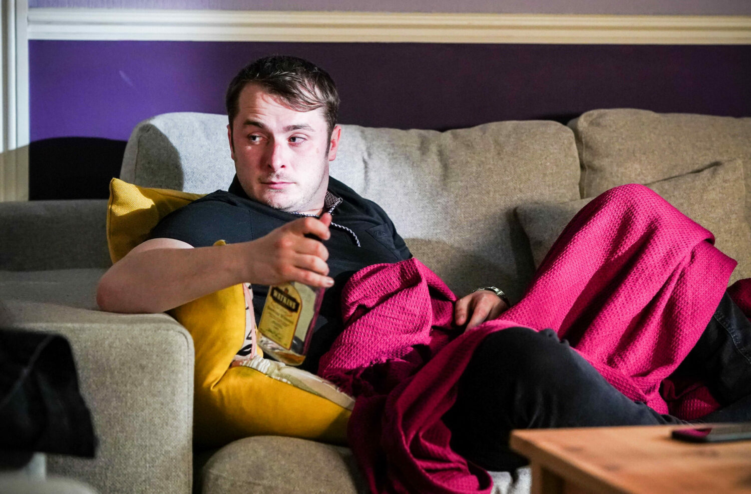 EastEnders Ben looks bedraggled on the sofa under a pink blanket